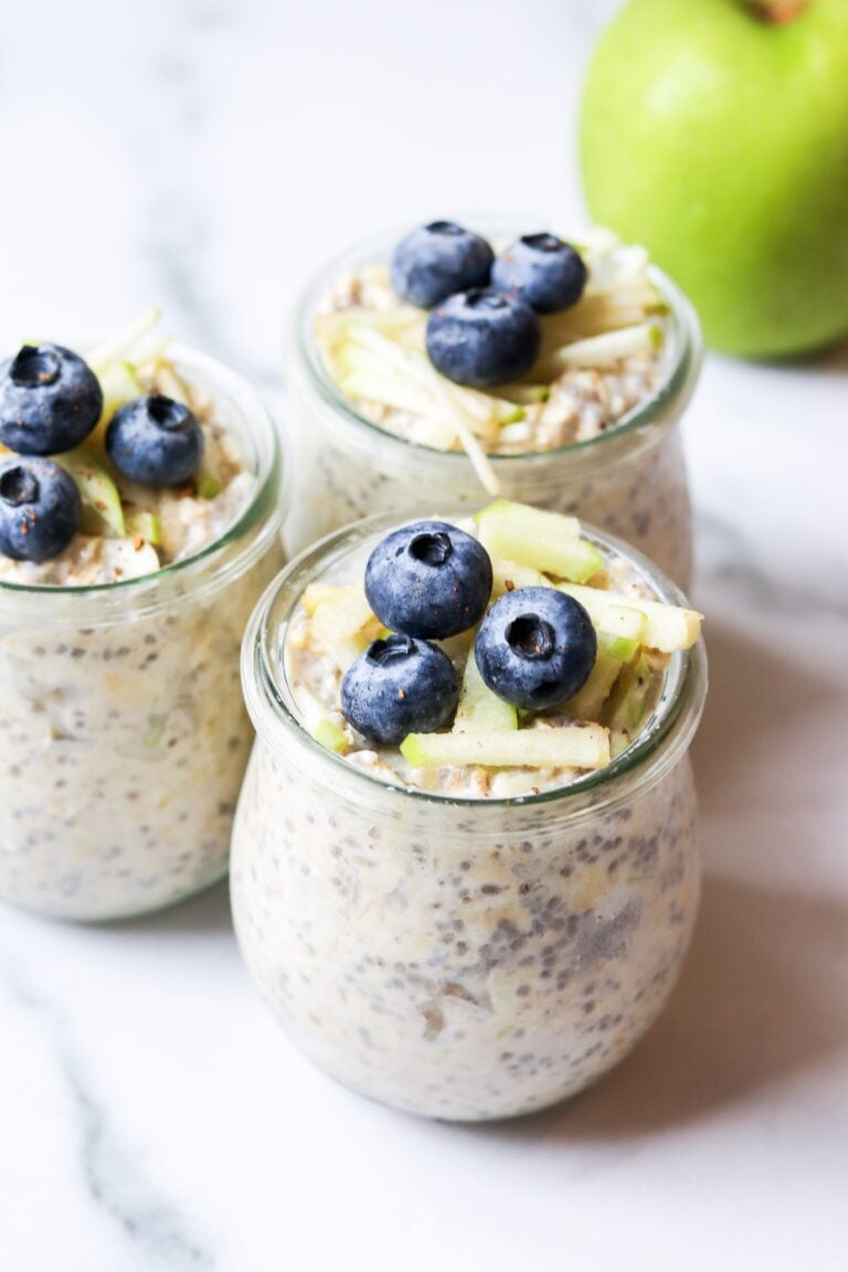 Three jars of overnight oats topped with blueberries and green apple