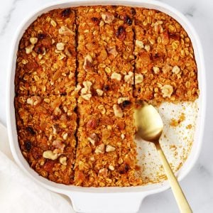 White baking dish with carrot cake baked oatmeal and a gold serving spoon