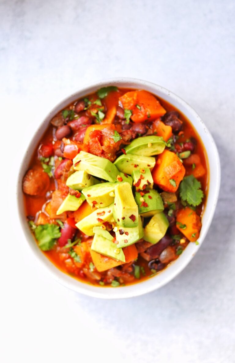 Bowl of butternut squash chili topped with chunks of avocado