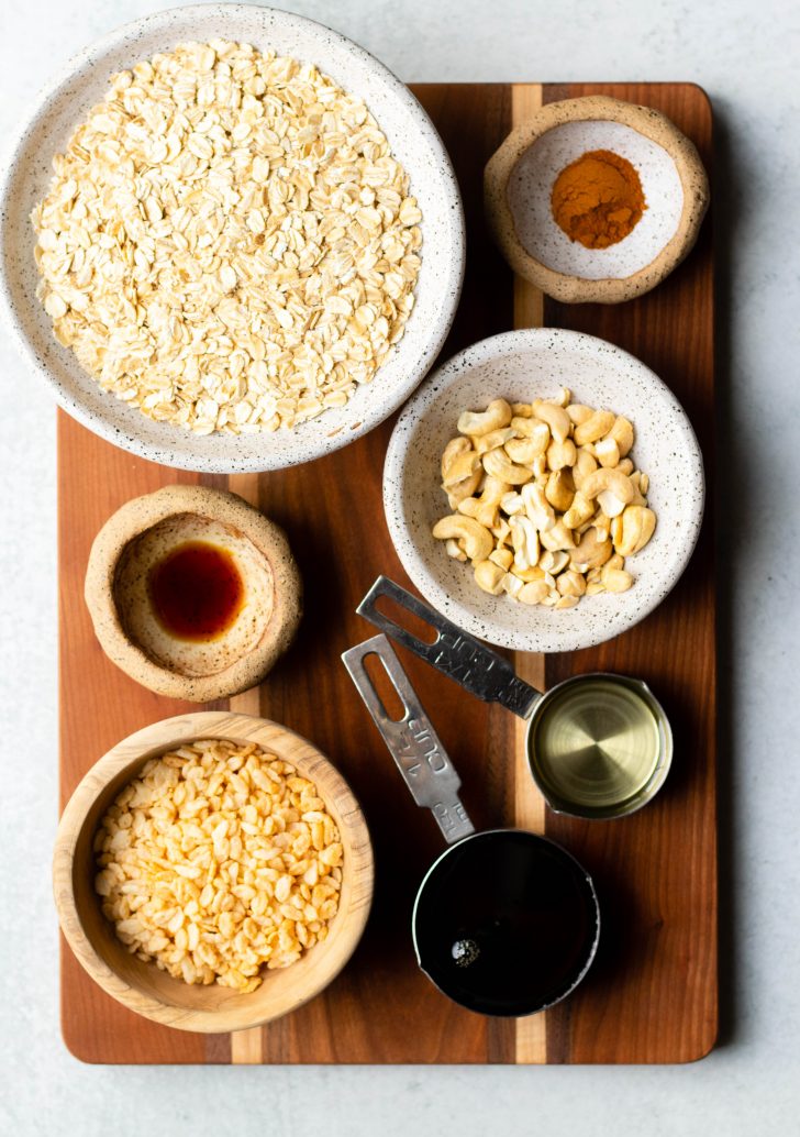 Cinnamon crunch granola ingredients measured out in bowls on a wooden cutting board