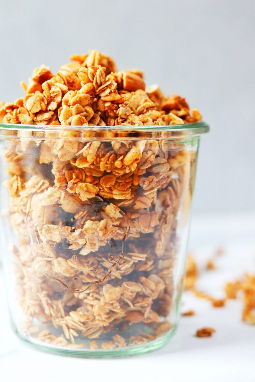 Close up of a glass jar filled to the brim with cinnamon granola