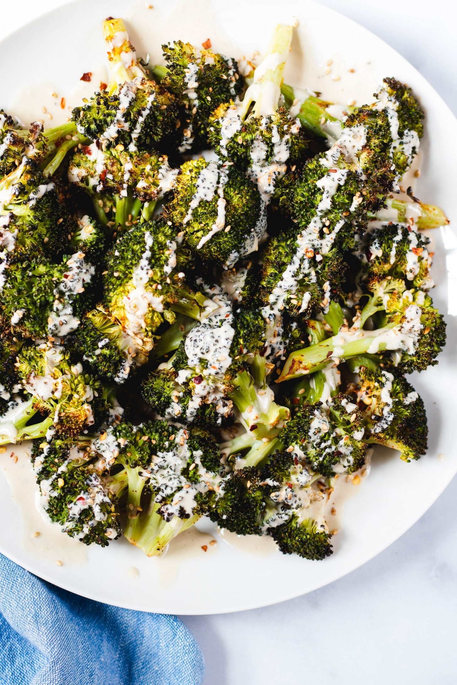Plate of roasted broccoli drizzled with lemon tahini sauce 