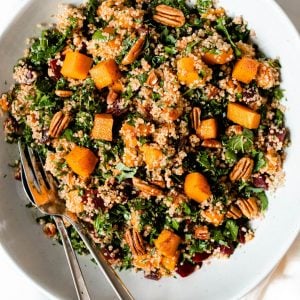 Bowl of beet quinoa salad mixed together with gold serving spoons