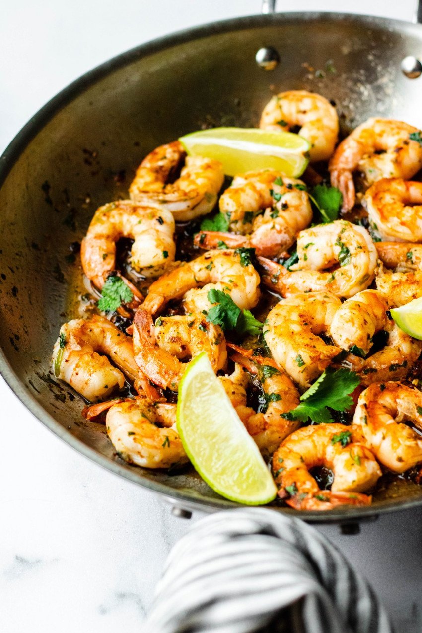Cooked cilantro lime shrimp in a frying pan with slices of limes