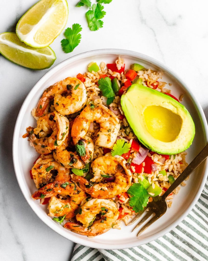 Cilantro lime shrimp in a bowl with rice, avocado and lime wedges