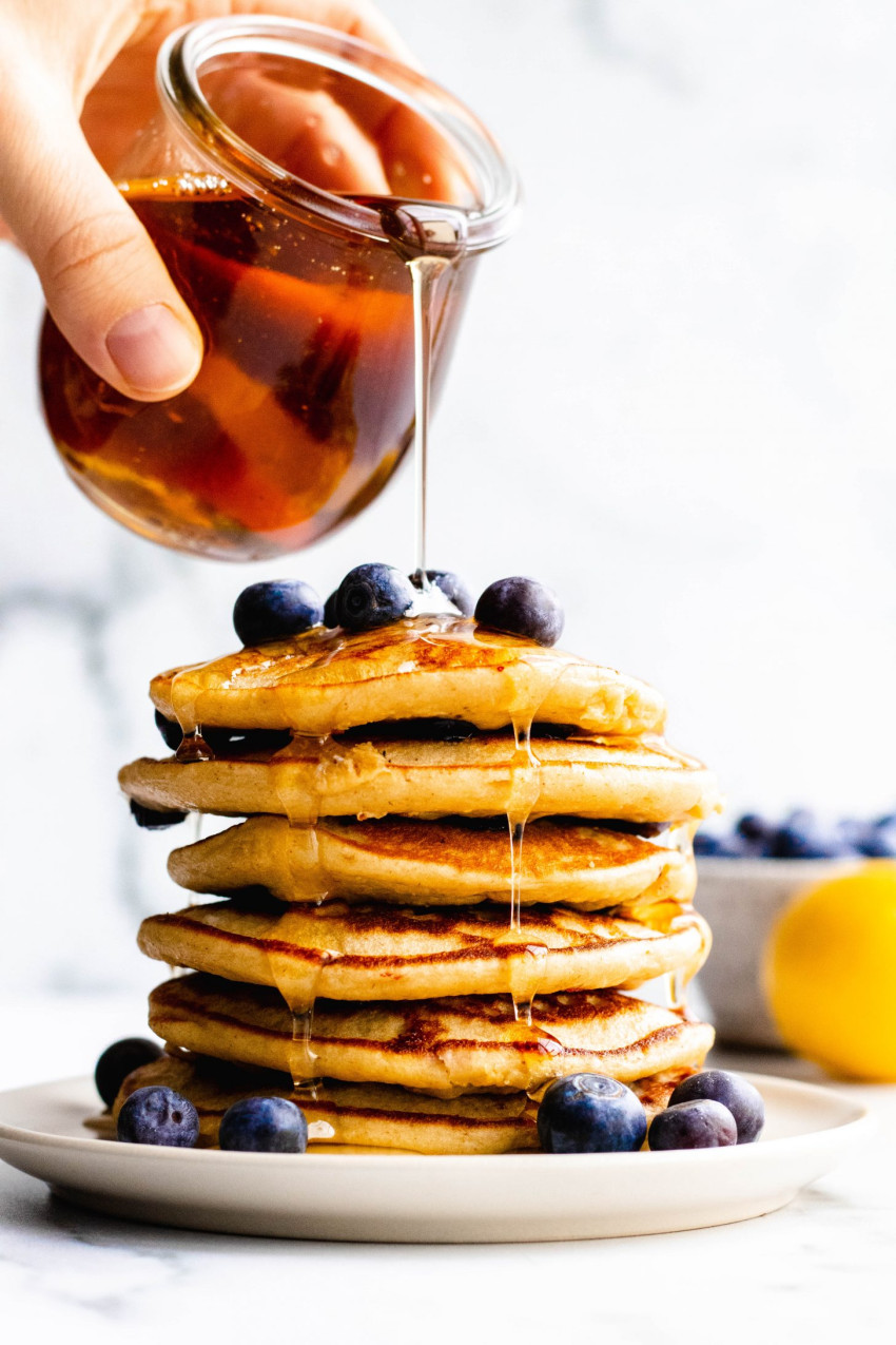 Stack of lemon blueberry cottage cheese pancakes being drizzled with maple syrup