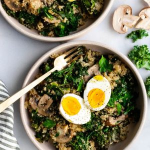 Two bowls of mushroom and kale quinoa with hard boiled eggs.