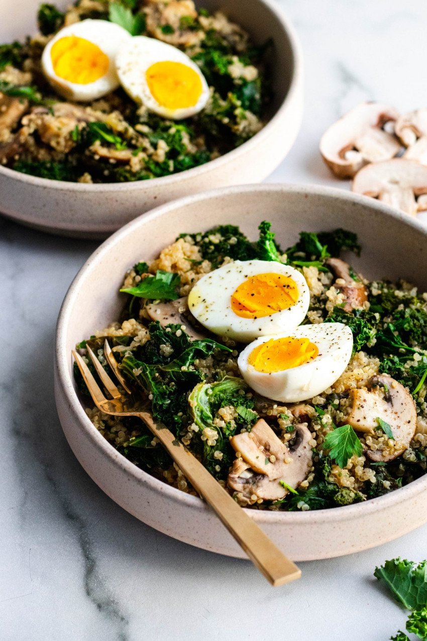Two bowls of mushroom and kale quinoa topped with hard boiled eggs