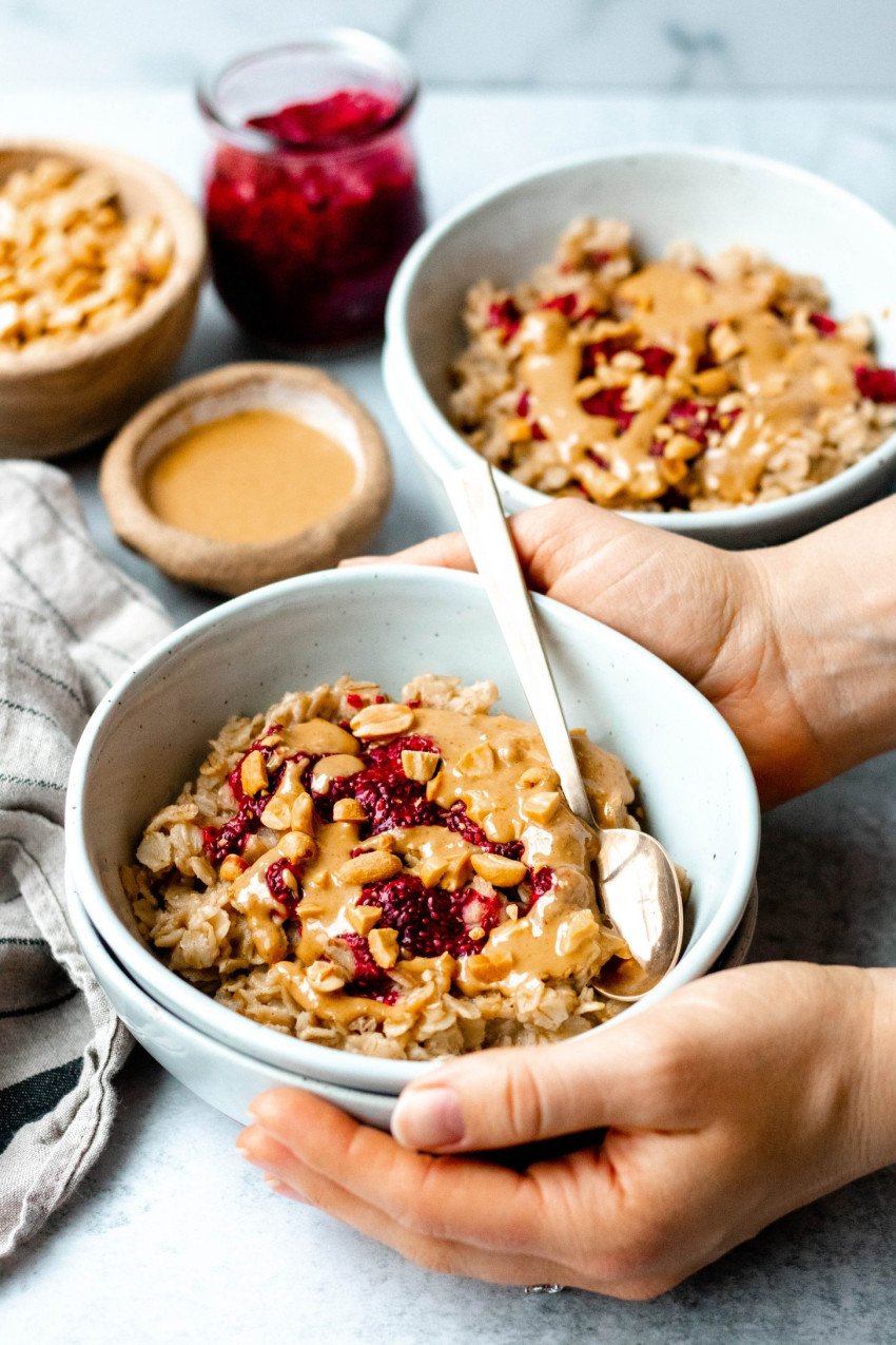 Two hands around a bowl of peanut butter and jelly oatmeal
