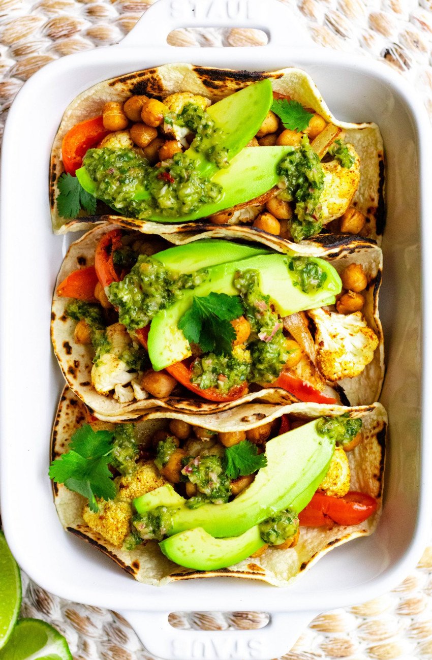 Three roasted veggie and chickpea tacos in a white baking dish