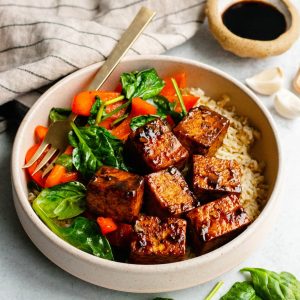Honey balsamic tofu bowl with rice and sauteed vegetables with ingredients scattered around the bowl