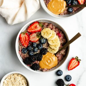 2 bowls of berry banana stovetop oatmeal with fresh berries, banana slices, and peanut butter