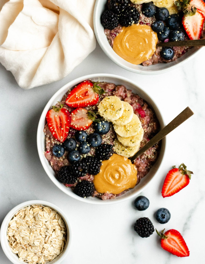 Two bowls of berry banana stovetop oatmeal with fresh berries, banana slices, and peanut butter
