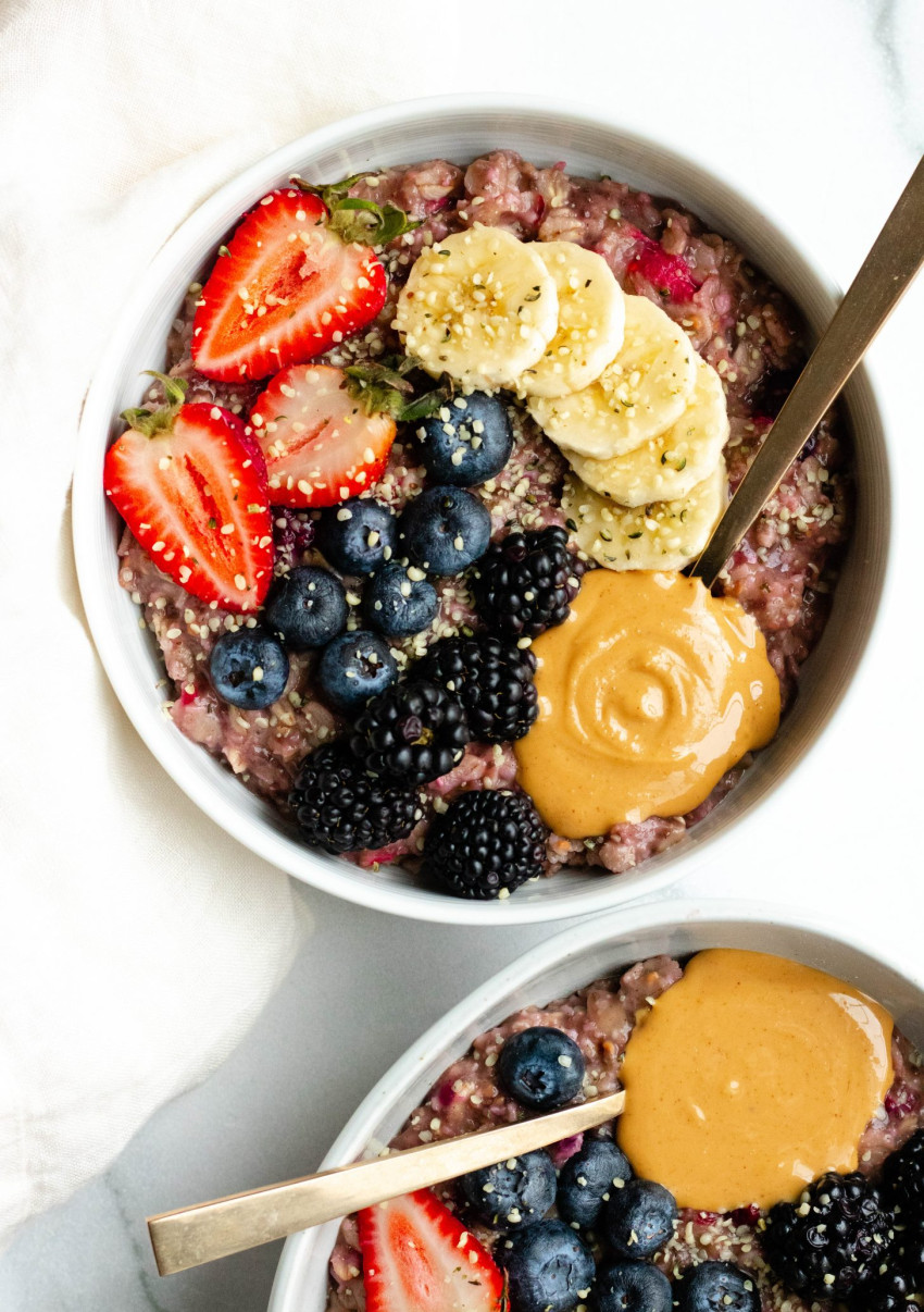 Close up image of a bowl of berry banana stovetop oatmeal with fresh berries, banana slices, and peanut butter