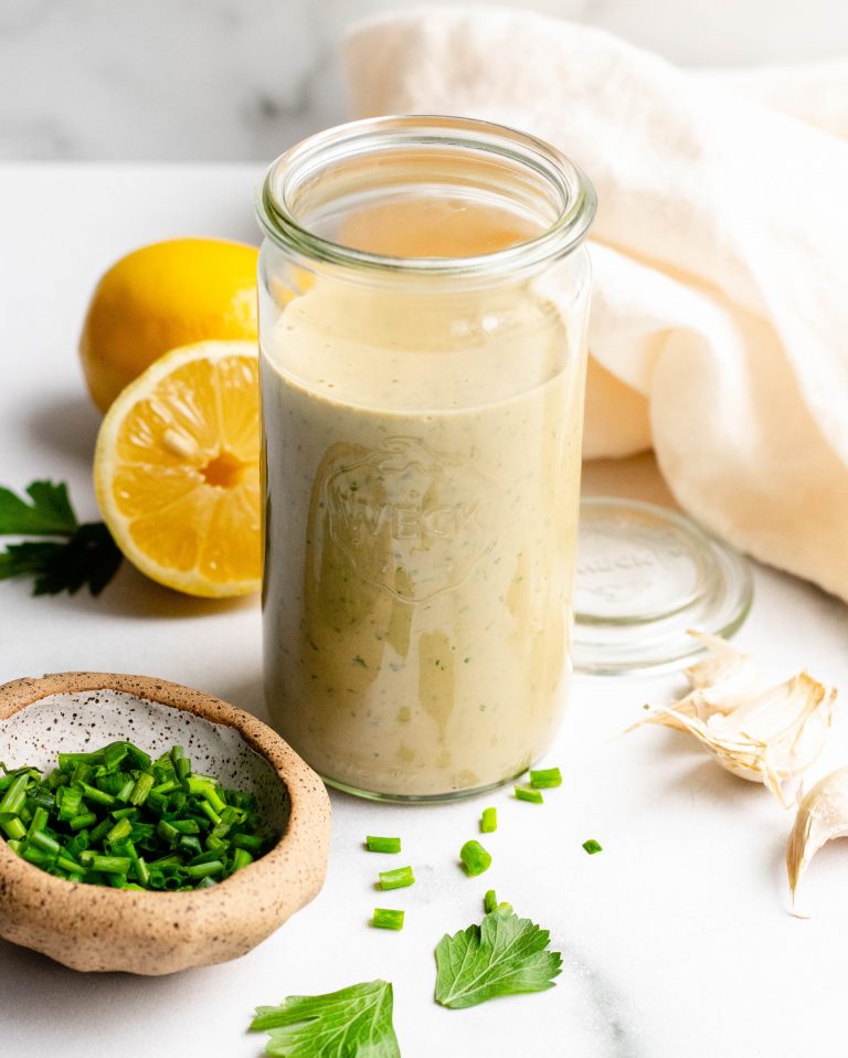 Healthy Tahini Goddess Dressing in a jar with ingredients around the jar