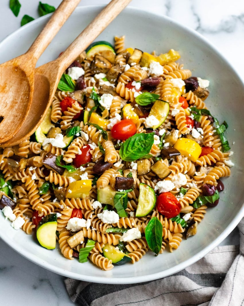 Healthy Roasted Vegetable Pasta Salad in a large bowl with wooden mixing spoons