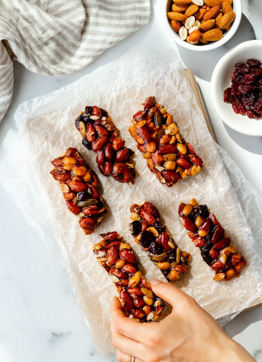 6 homemade honey nut KIND bars on wax paper with a hand taking one away