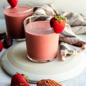 Two red velvet smoothies in glass cups garnished with strawberries