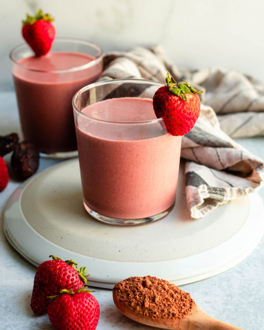 Two red velvet smoothies in glass cups garnished with strawberries