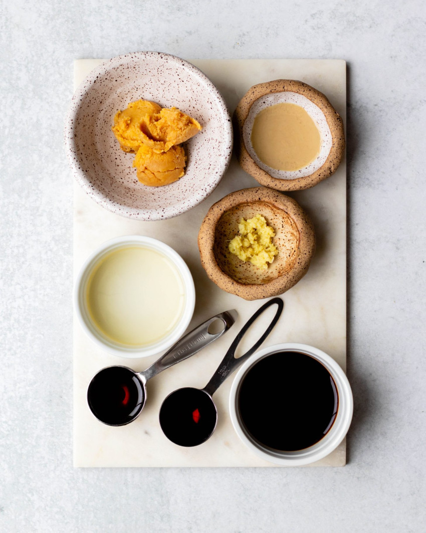 Sesame ginger miso dressing ingredients in measuring utensils on a white board