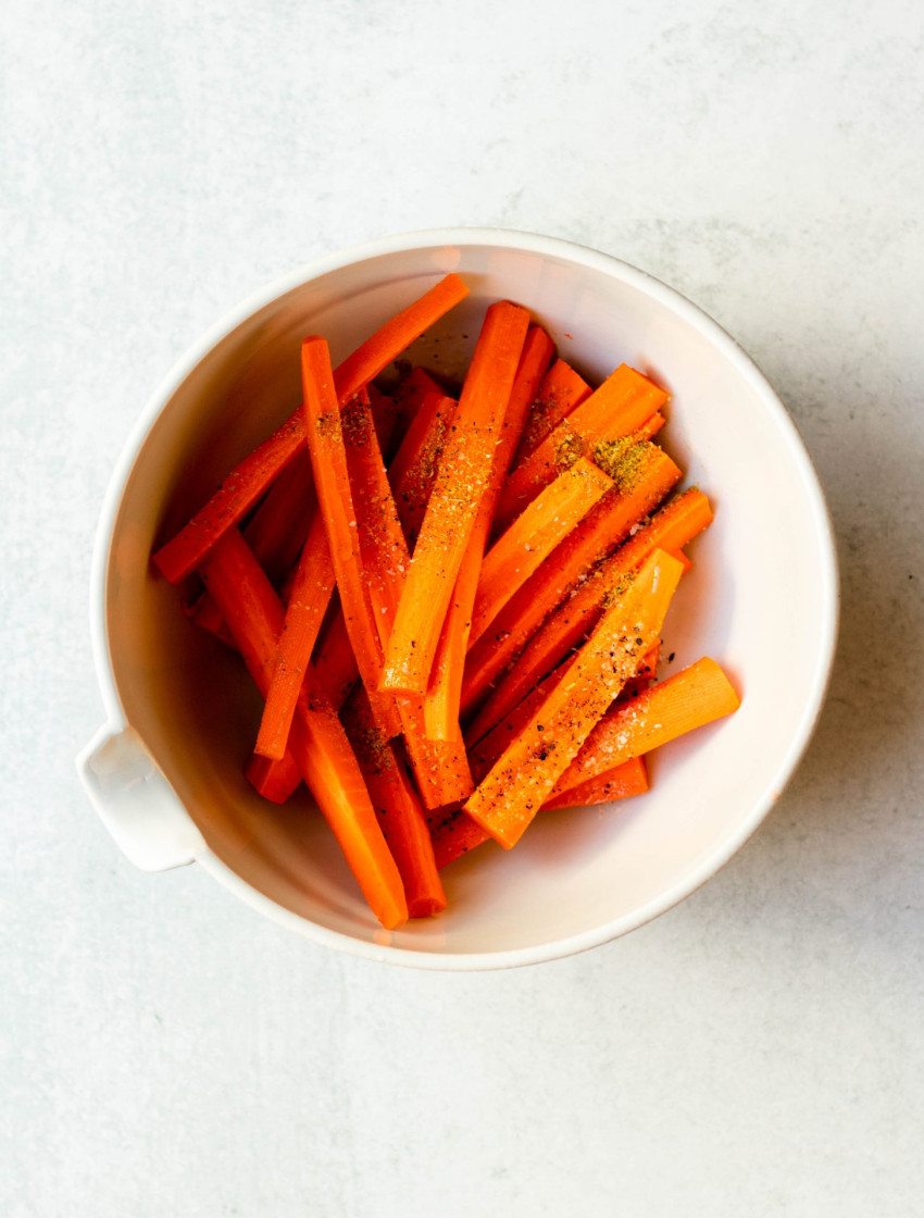 Carrot fries in a mixing bowl before cooking