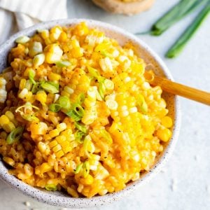 Close up of a bowl of vegan miso corn risotto with a wooden spoon, and bowl of miso paste in the background