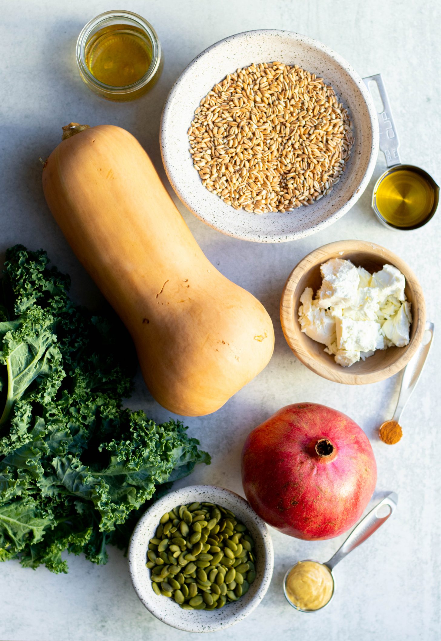 Fall farro salad ingredients measured out on a grey backdrop