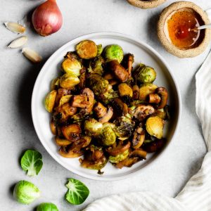 Bowl of sauteed Brussels sprouts and mushrooms surrounded by ingredients