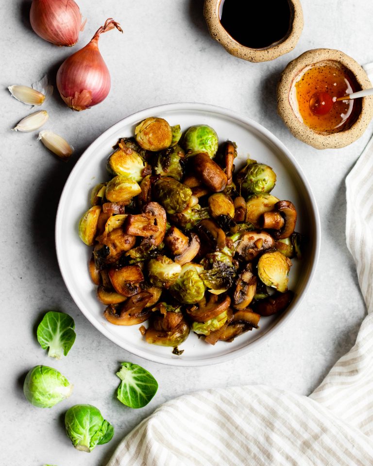 Bowl of sauteed Brussels sprouts and mushrooms surrounded by ingredients