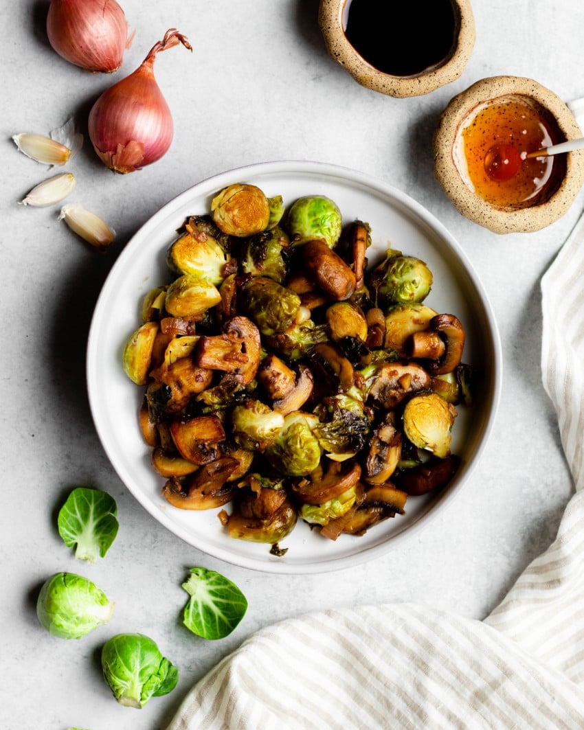 Bowl of sauteed Brussels sprouts and mushrooms surrounded by ingredients