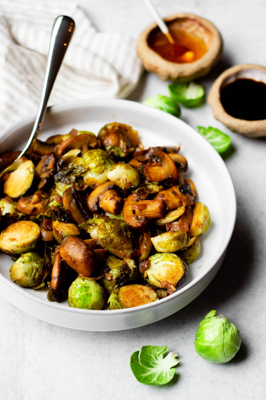 Bowl of sauteed Brussels sprouts and mushrooms surrounded by ingredients