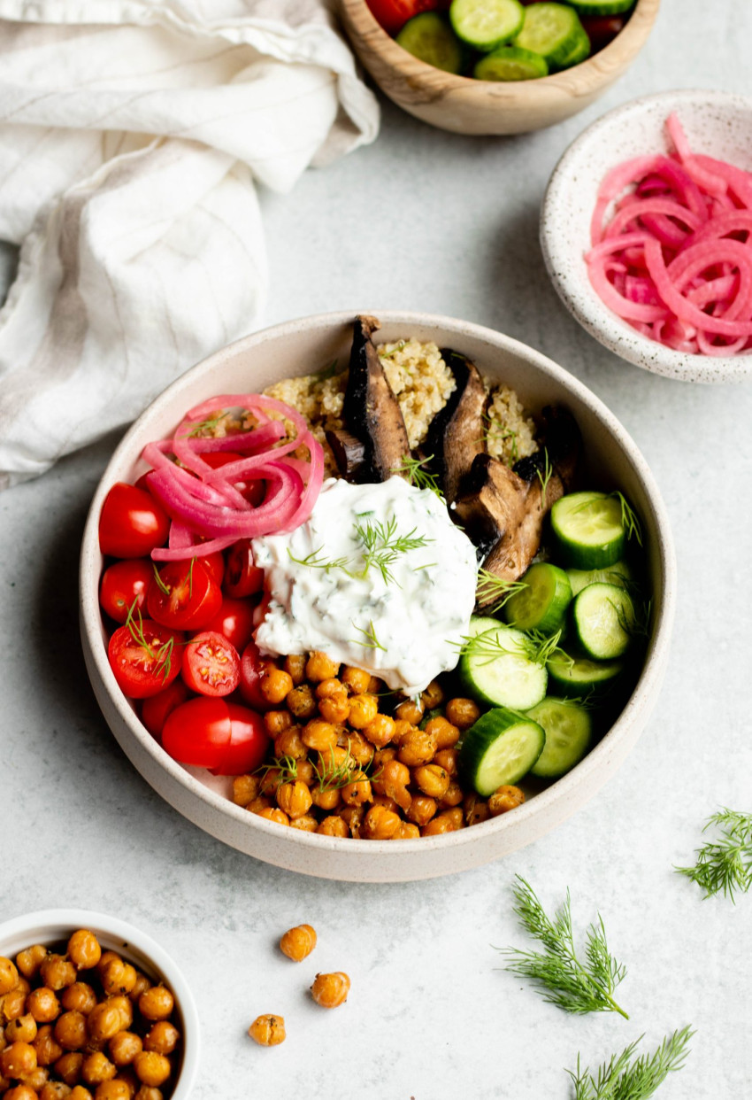 Vegetarian gyro bowl on grey backdrop surrounded by ingredients