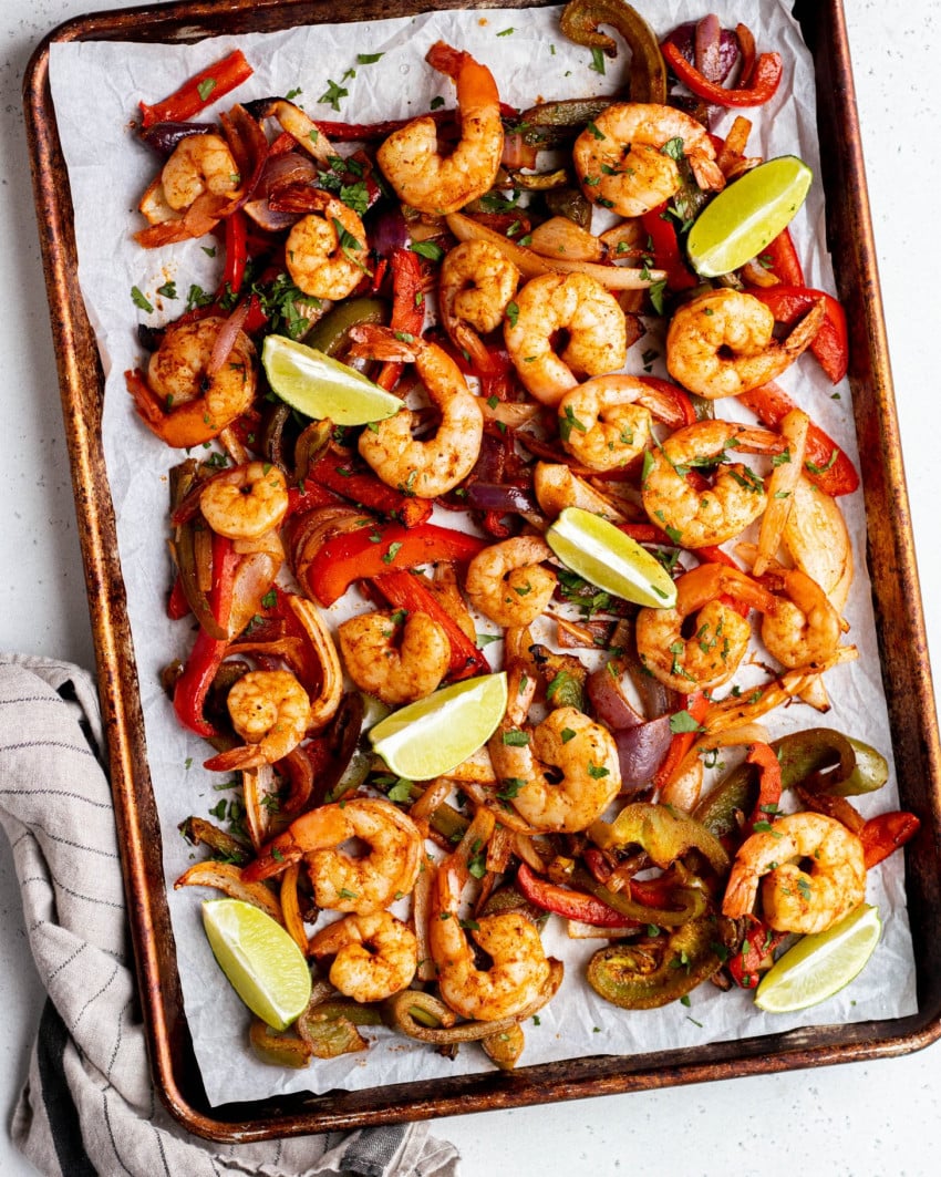 Roasted peppers, onions, and shrimp on a sheet pan with lime slices
