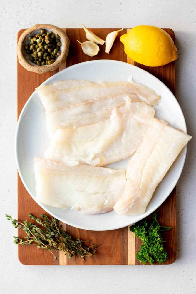 lemon caper baked cod ingredients measured out on a wooden cutting board