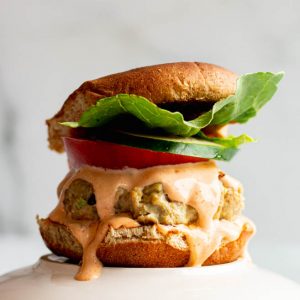 Fresh tuna burger on a bun with lettuce, cucumber, tomato, dripping with spicy mayo