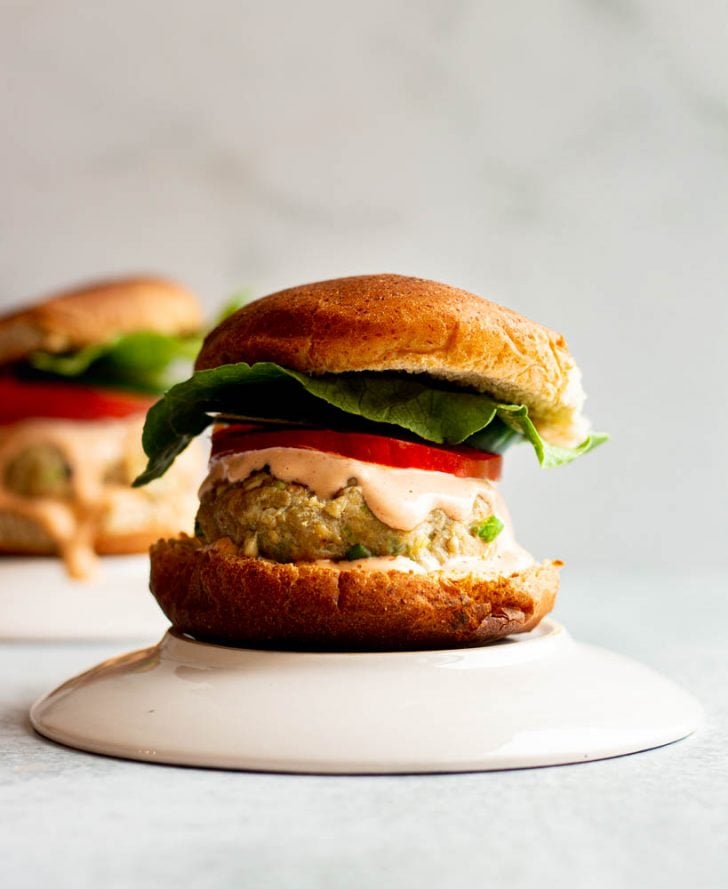 Fresh tuna burger on a bun with lettuce, cucumber, tomato, dripping with spicy mayo