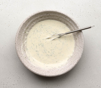 greek yogurt salad dressing in a speckled bowl with a small whisk