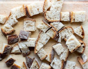 Bread cut into chunks on wooden cutting board