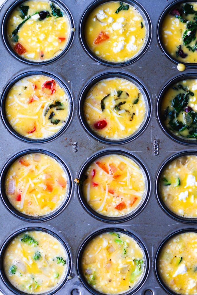 Mini frittatas with veggies and cheese in a muffin tin before being baked