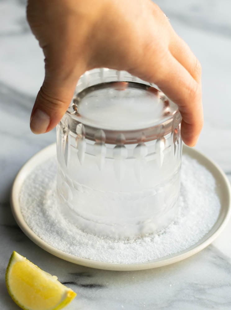 hand salting the rim of a glass for a margarita