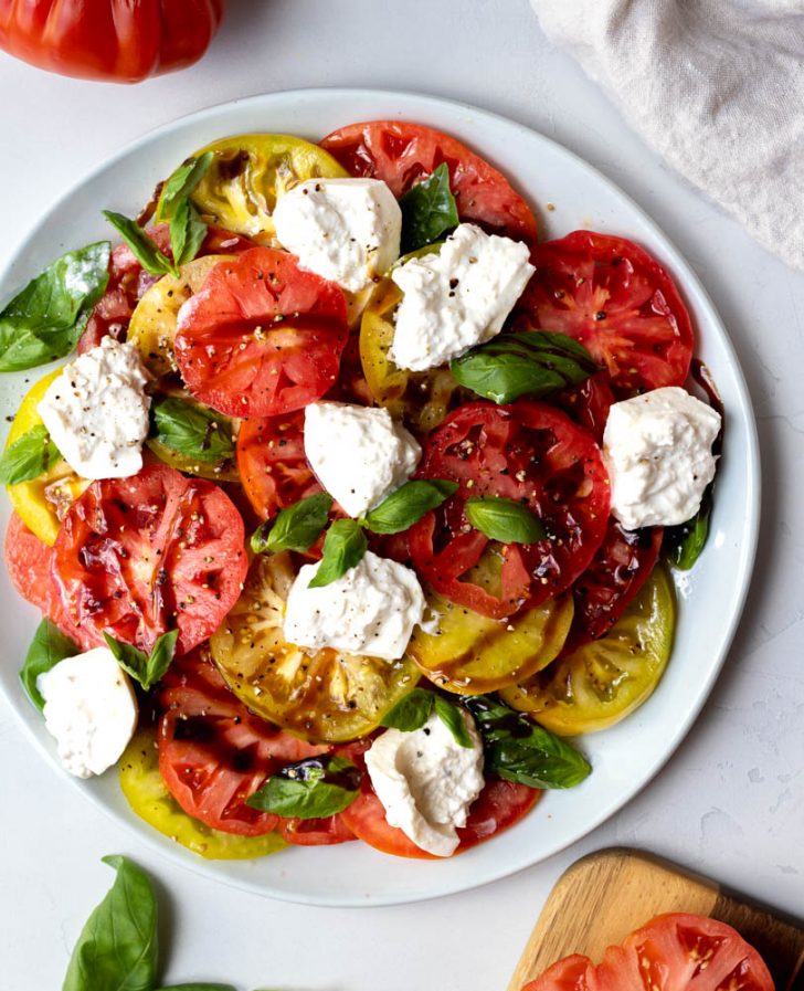 heirloom tomato and burrata salad with balsamic glaze on a light grey backdrop