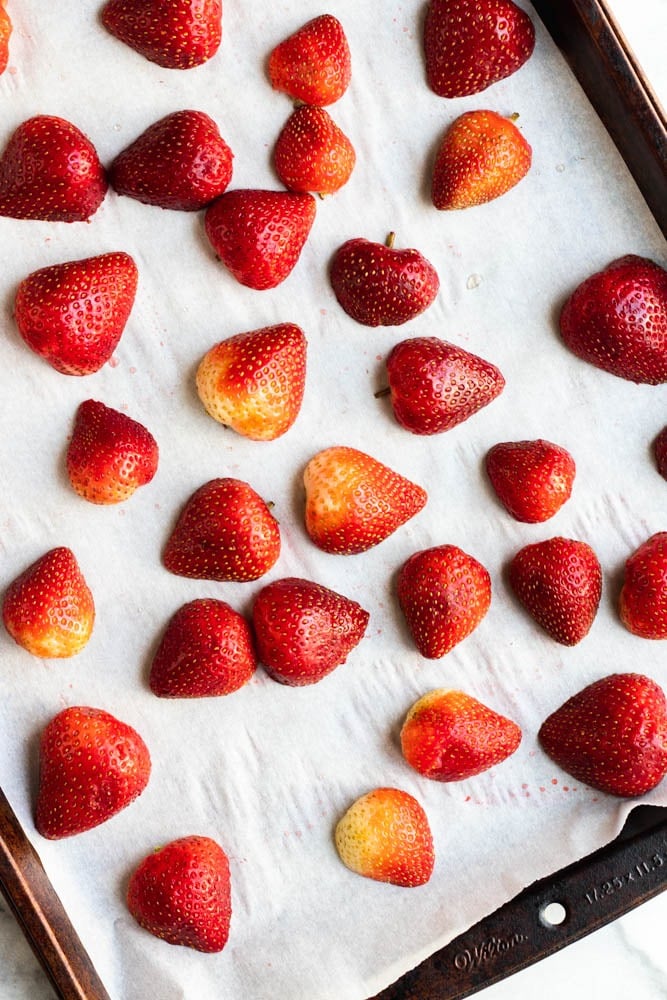 cut strawberries on a parchment paper lined baking sheet