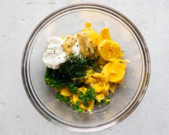Egg salad ingredients in a mixing bowl before being mixed together
