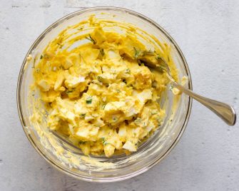 Creamy egg salad in a glass mixing bowl
