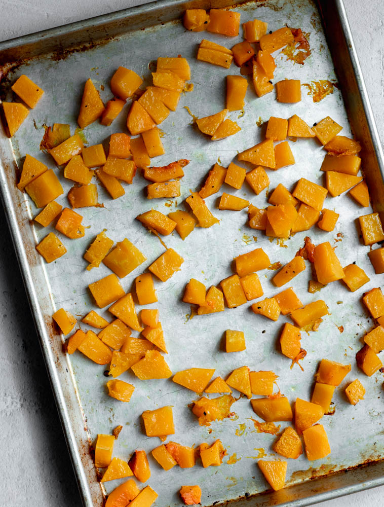 Roasted butternut squash cubes on a baking sheet