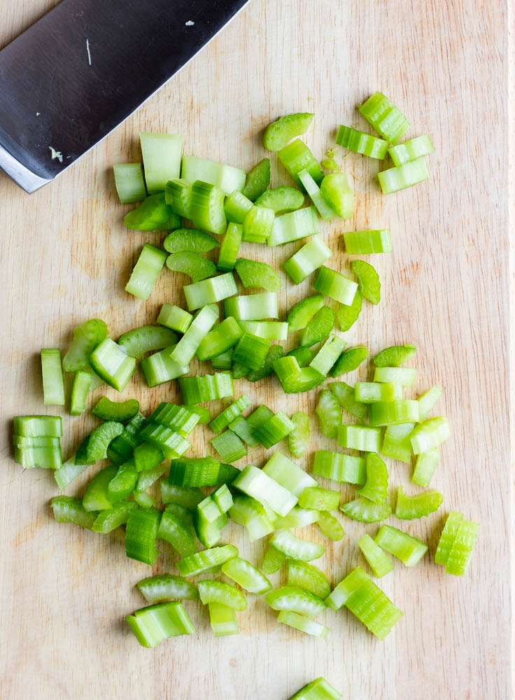 diced celery on a wooden cutting board