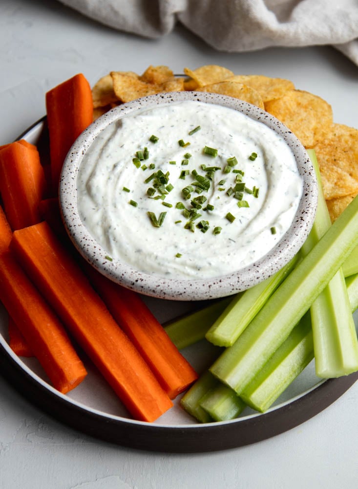 plate of Greek yogurt ranch dip with veggie sticks and potato chips
