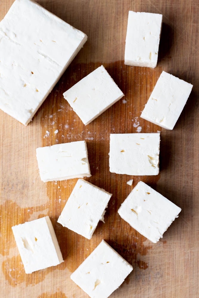 cubes of feta cheese on a wooden cutting board