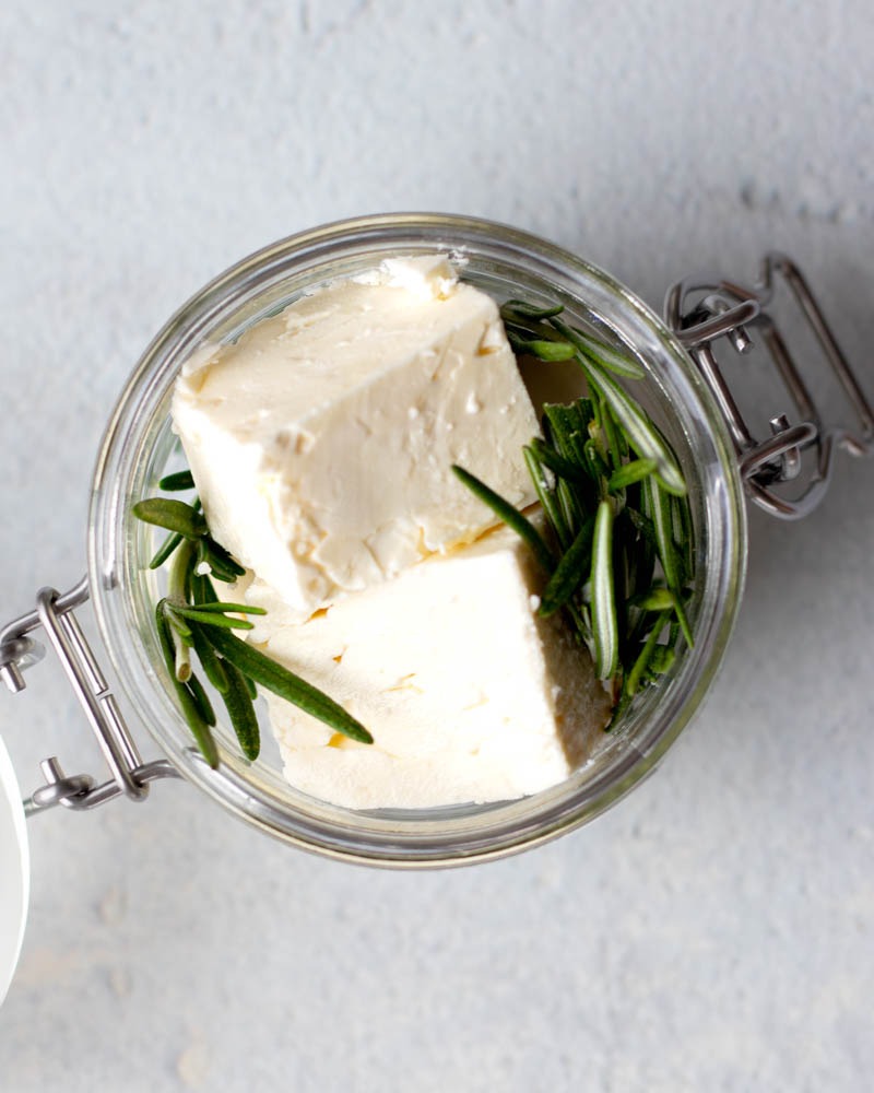 cubes of feta cheese and rosemary in a small jar