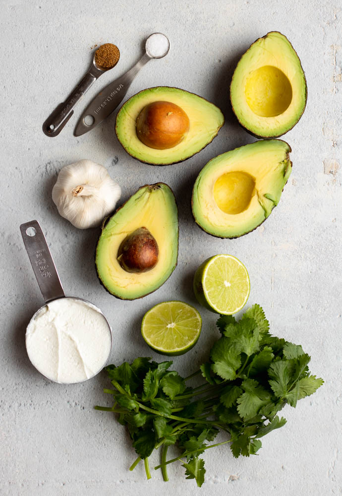 Avocado greek yogurt dip ingredients measured out on a light grey backdrop